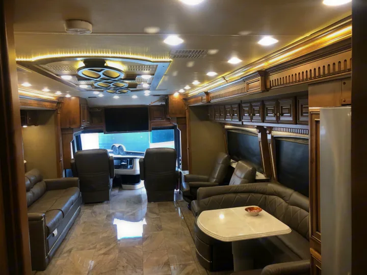 Step into this high-end RV rental's spacious living area: leather sofas, dining booth, tiled floor, and driver's cockpit.. Monaco Signature 2020