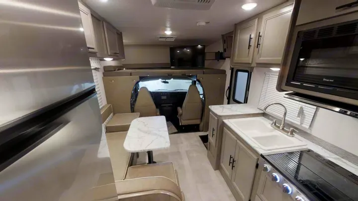Spacious rv rental interior showing kitchen, dining booth, and bed over cab. Modern and clean design.. Coachmen Freelander 2021