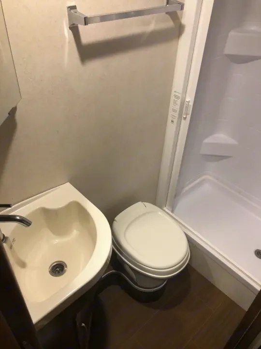 RV rental bathroom featuring a shower with door, toilet, and small corner sink. Practical and compact design for travel.. Winnebago Mercedes Sprinter 2020