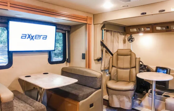 Spacious RV rental interior features a dining area, Axxera TV, and driver's cockpit. Ideal for comfortable travel.. Other Hurricane 2019