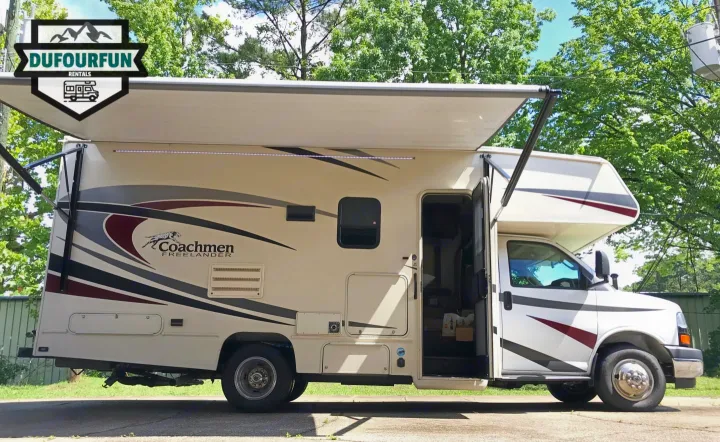 Side view of a light-colored Coachmen Freelander RV rental with extended awning and open door.. Coachmen Freelander 2018