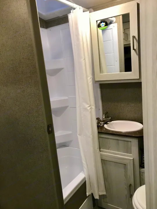 RV rental bathroom. Features a small tub/shower combo, vanity with sink, and mirrored cabinet, showcasing compact design.. Other Other 2021