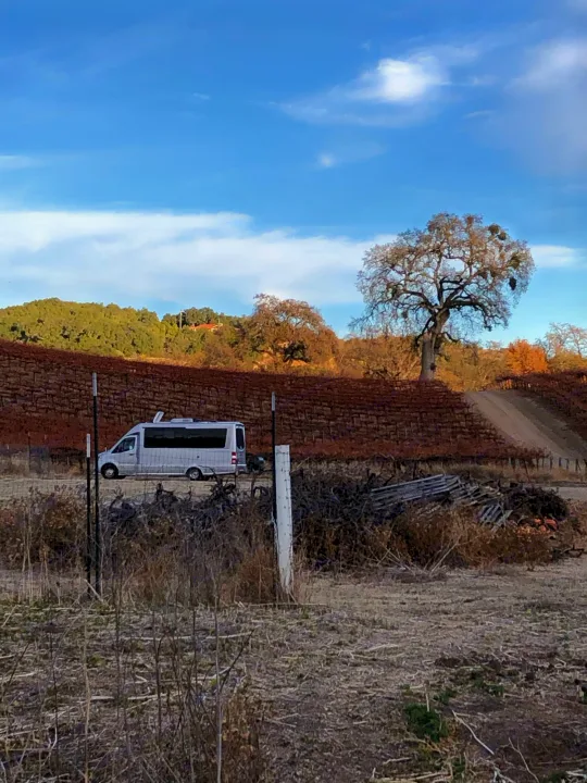 White RV rental parked beside a dormant vineyard with rolling hills & oak trees, perfect for a scenic trip.. Airstream Atlas 2021