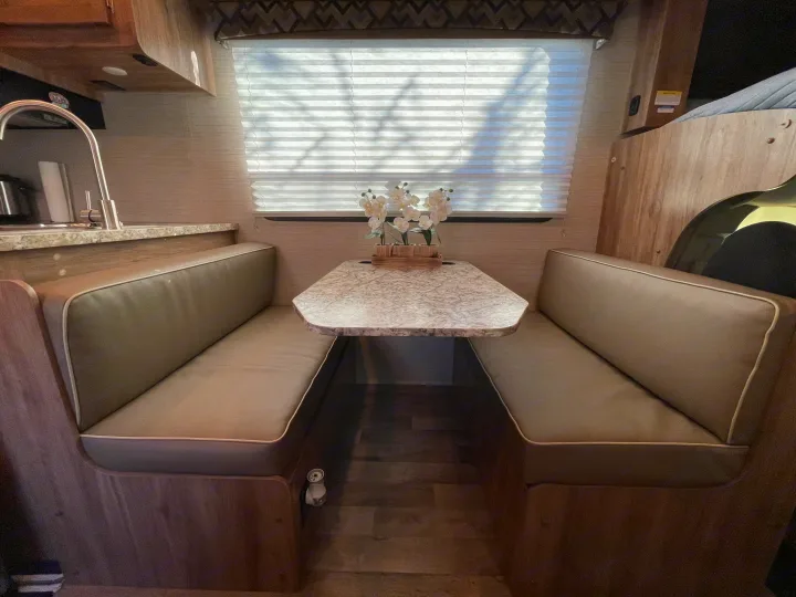 This rv rental features a cozy dinette with two cushioned bench seats, a tabletop, and a large window with blinds.. Jayco Redhawk 2020