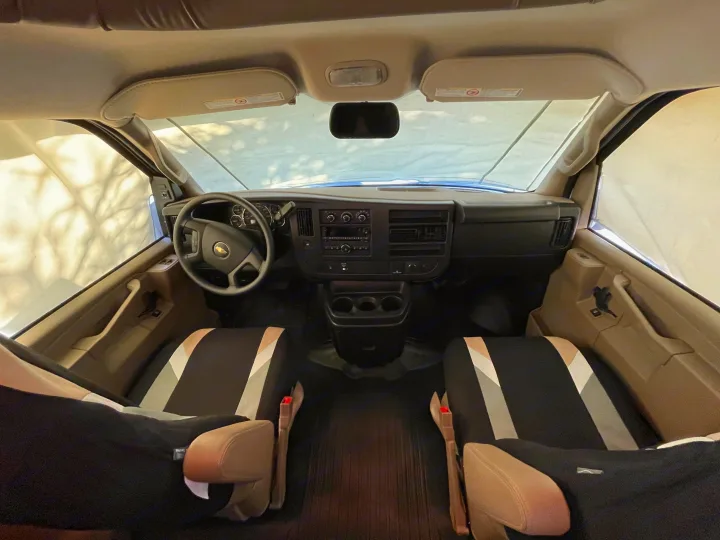 Spacious RV rental interior featuring front seats, dashboard, and steering wheel, viewed from the back.. Jayco Redhawk 2020