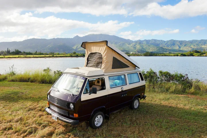 Brown & beige VW Westfalia pop-top camper van (RV rental) by a lake with scenic mountains. Ready for adventure!. Volkswagen Westfalia 1985