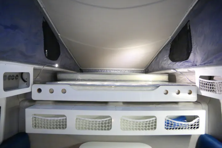 Inside an RV rental, showcasing its practical pop-top sleeping area with stacked beds, new mattresses, and netted storage.. Other Other 2021