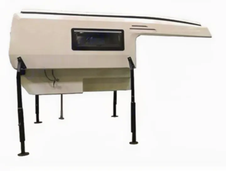 A white, detached truck camper unit with a window, standing on four black adjustable legs. Ideal for RV rental trips or camping.. Other Other 2021