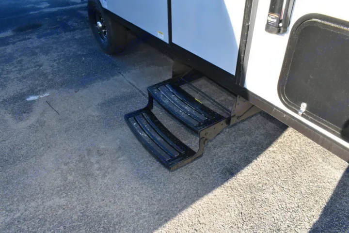 An RV rental's black two-step entry system is extended onto sunlit pavement, ready for easy access.. Forest River Salem 2021
