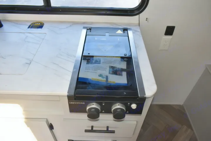 RV rental kitchen showing a compact Greystone cooktop with glass cover, sink area, and marble-look counter.. Forest River Salem 2021