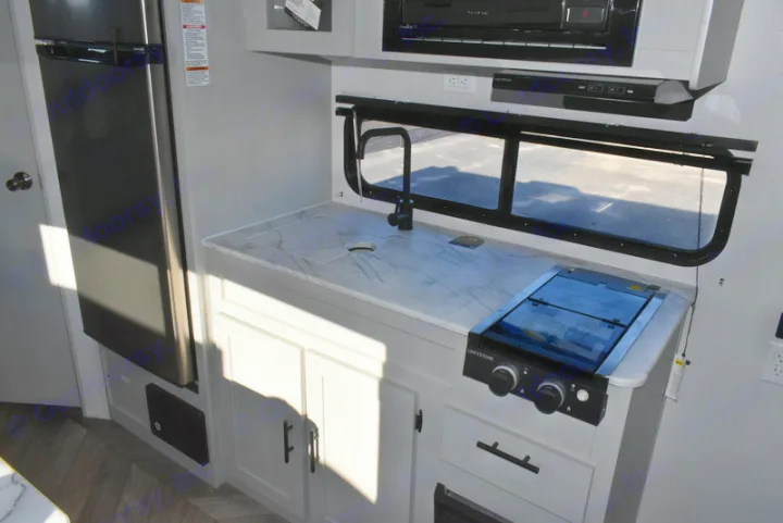 RV rental kitchen interior: features a modern countertop, sink, Greystone stove, fridge, and cabinets.. Forest River Salem 2021