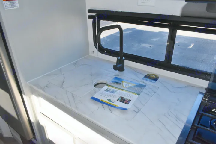 Inside an RV rental, a clean kitchen features a marbled countertop, compact sink with cover, and modern black faucet.. Forest River Salem 2021