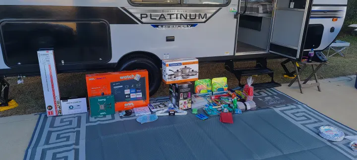 New gear and accessories for a comfortable RV rental camping trip, spread on a mat beside a Forest River travel trailer.. Forest River Salem 2021