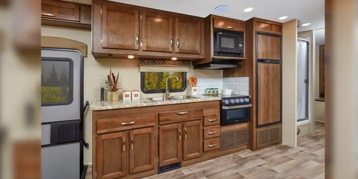 Explore this RV rental's well-equipped kitchen: wood cabinets, double sink, microwave, oven, and fridge.. Jayco Redhawk 2020
