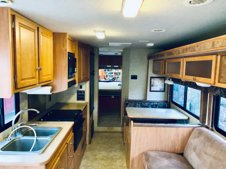 Inside a cozy RV rental: a well-equipped kitchen, comfortable dining booth, and rear bedroom.. Winnebago ITASCA 2009