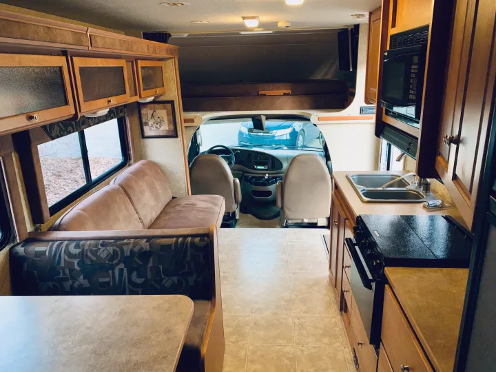 Spacious RV rental interior with a full kitchen, dinette, sofa, and cab-over bunk. Ready for your next adventure.. Winnebago ITASCA 2009