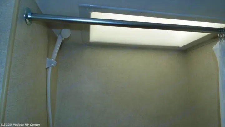 RV rental shower interior, featuring a handheld sprayer, curtain rod, and bright overhead light for convenience.. Eclipse Recreational Vehicles Milan 2013