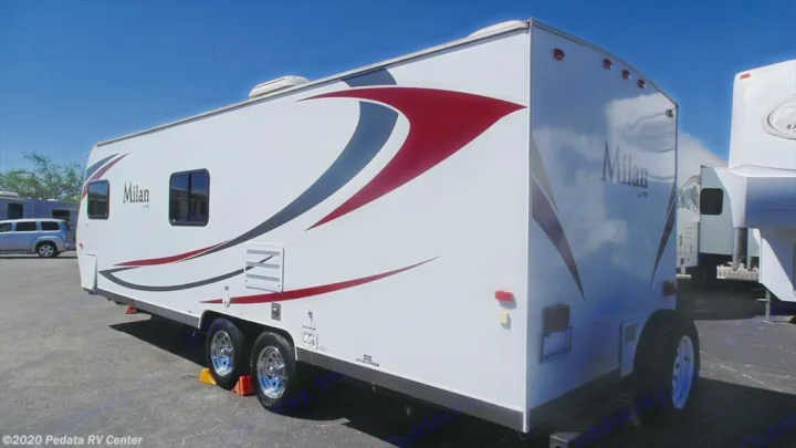 White Milan Lite travel trailer RV available for RV rental, with bold red and gray graphics, parked on a sunny day.. Eclipse Recreational Vehicles Milan 2013