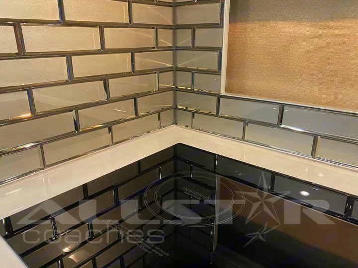 Modern RV rental kitchen corner: sleek gray subway tile backsplash, white counter, and black induction cooktop.. Fleetwood Pace Arrow 2021
