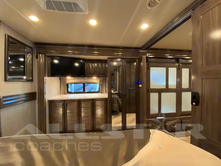Spacious RV rental bedroom featuring a TV, cabinets, and sliding door for comfortable journeys.. Fleetwood Pace Arrow 2021