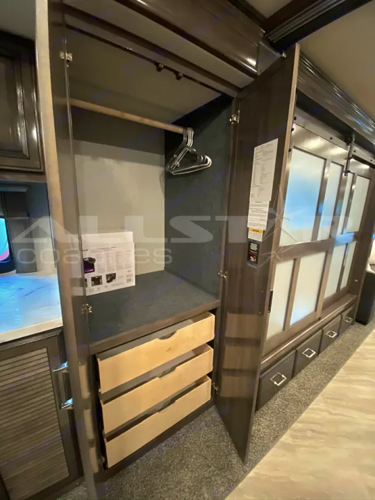 Spacious RV rental closet featuring a hanging rod, hangers, and three drawers for convenient storage.. Fleetwood Pace Arrow 2021