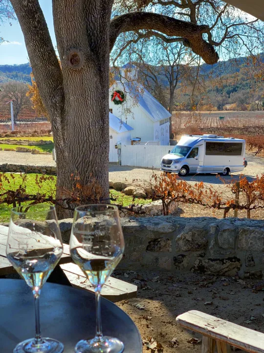 Wine tasting at a scenic vineyard, with an RV rental by a white barn and mountain views.. Airstream Atlas 2021