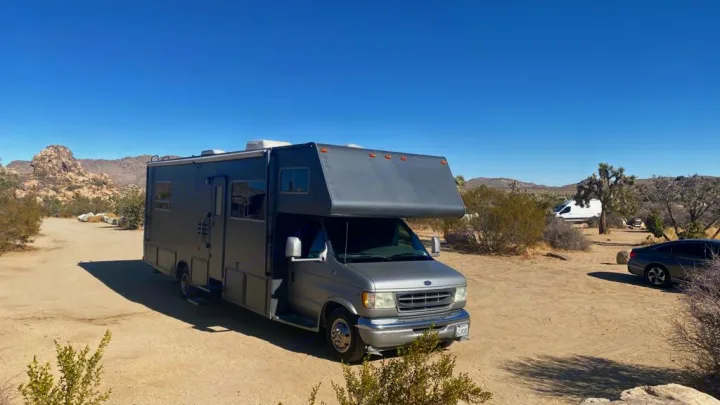 Gray RV on a sunny desert campsite with rocks & Joshua trees. Your perfect RV rental for an outdoor travel adventure.. Jayco Greyhawk 2002
