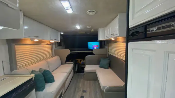 Inside an RV rental: bright, spacious living area with comfortable seating, overhead cabinets, and a TV for your journeys.. Jayco Greyhawk 2002