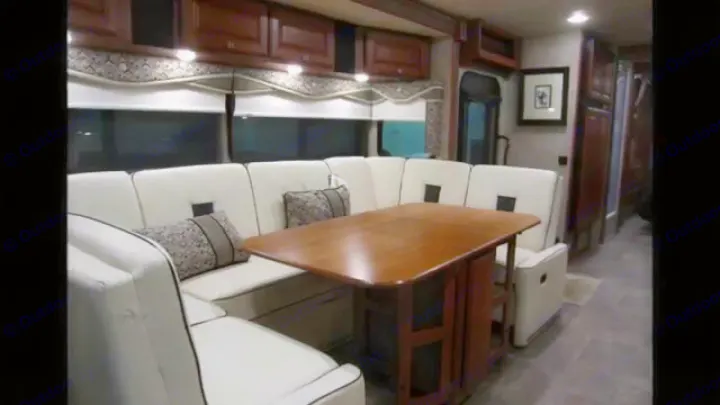 Inside this RV rental, find a comfortable cream U-shaped dinette with a wood table, framed art, and overhead storage.. Winnebago Sightseer 2015