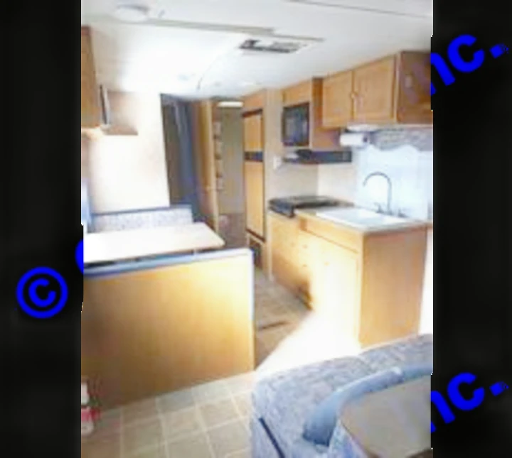 View of kitchen sink, stove top, microwave, refrigerator, and dining table. Dutchmen Sport 2004