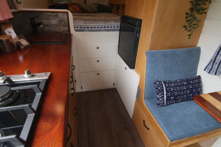 RV rental interior with a compact kitchen, comfortable bed, refrigerator, and cozy seating area with storage drawers.. Mercedes-Benz Sprinter 2012