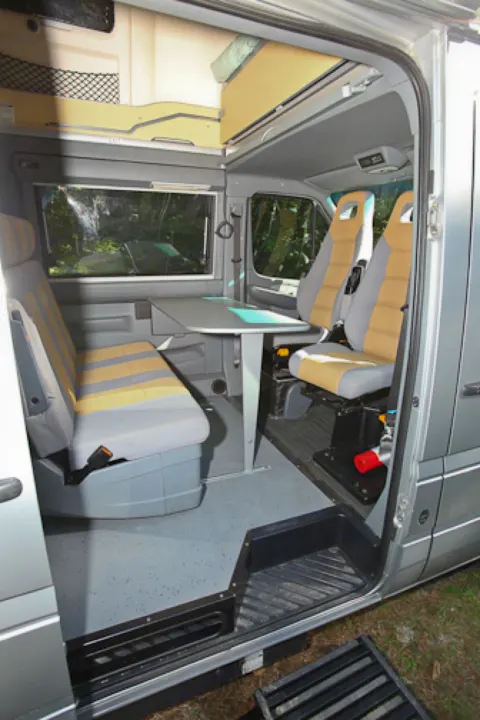 RV rental camper van interior: bright space with swivel seats, dining table, and cozy overhead sleeping area, ready for adventure.. Airstream Westfalia 2005
