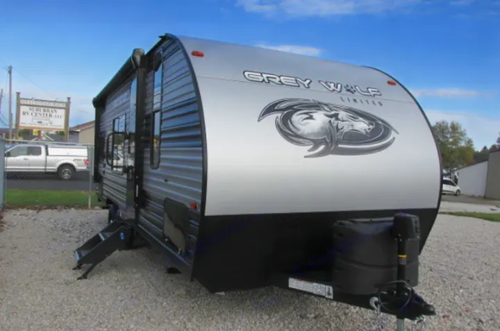 A modern Grey Wolf travel trailer, ideal for your next RV rental or camping trip, shown parked on gravel with steps down.. Forest River Cherokee Grey Wolf 2021