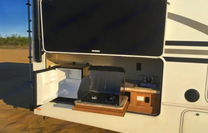 This RV rental features an outdoor kitchen with a mini-fridge, stove, and sink, perfect for convenient camping and outdoor cooking.. Entegra Coach Odyssey 25R 2019