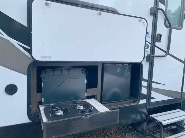 RV rental featuring an outdoor kitchen: pull-out two-burner stove, mini-fridge for easy camping meals.. Grand Design Imagine 2019