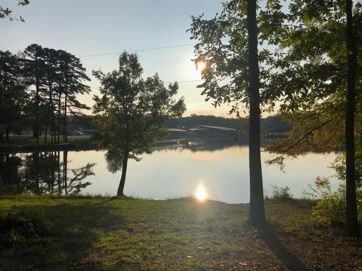 Serene lakeside view at sunset. Sun reflects on water, trees, & distant boat docks. Ideal for an RV rental getaway.. Forest River Other 2021