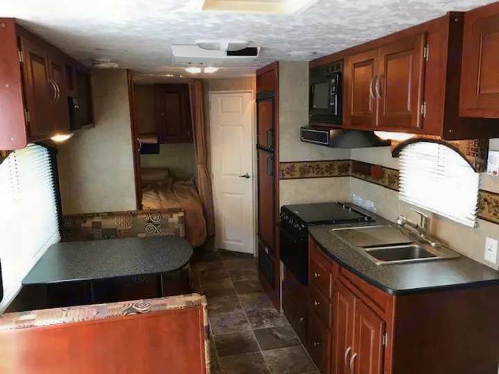 RV rental interior features a kitchen (stove, sink, microwave), a dinette, and bunk beds, offering comfort for travelers.. Wildwood Wildwood 2011