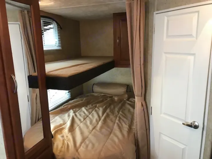 An RV rental's cozy bunk beds with windows and a cabinet, providing comfortable sleeping space.. Wildwood Wildwood 2011