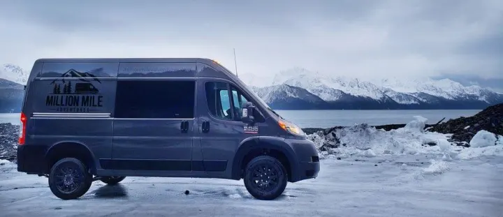 Million Mile Adventures RV rental van on icy shore, with snow-capped mountains across water. Your adventure starts!. Ram Promaster 2020