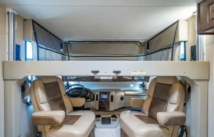 RV rental interior: The driver's cab with comfy seating and an overhead bunk bed, secured with a safety net, awaits adventure.. Other Hurricane 2017