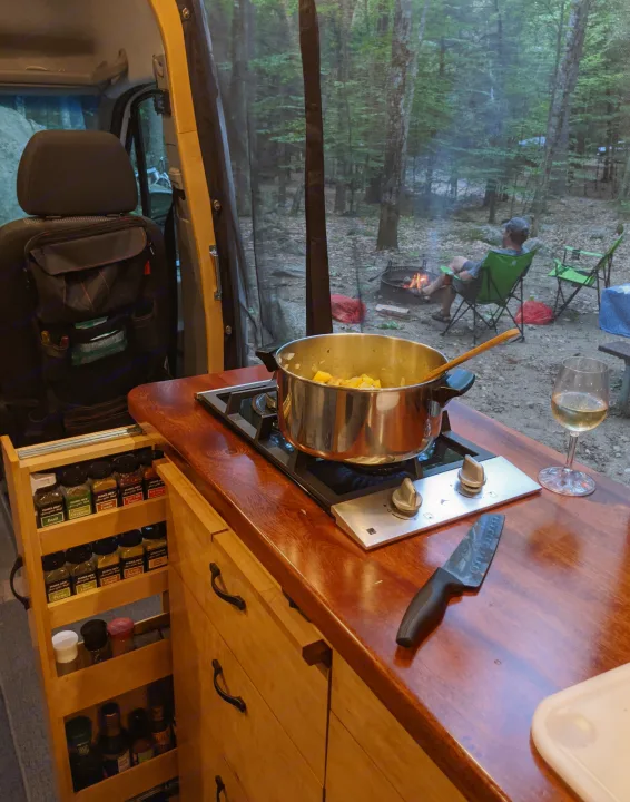 Cozy RV rental cooking: prepping dinner on the stove with a campfire view and a glass of wine.. Mercedes-Benz Sprinter 2012