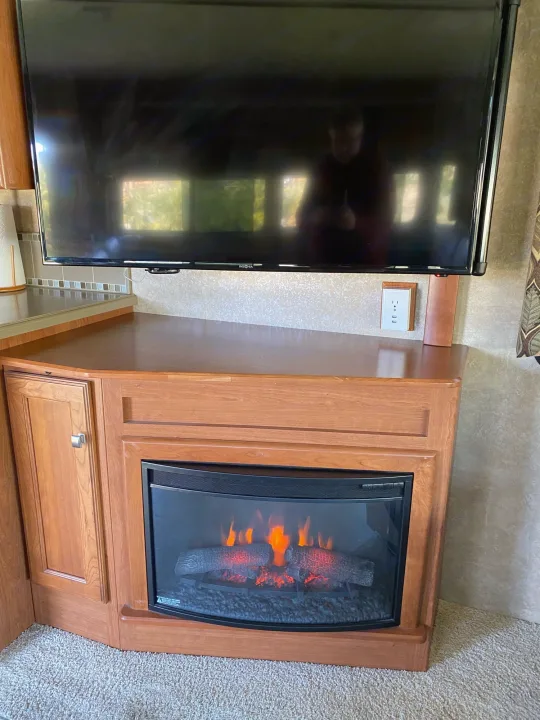 This cozy RV rental features a TV, an electric fireplace with realistic logs, and warm wooden cabinetry and countertop.. Winnebago Sightseer 2015