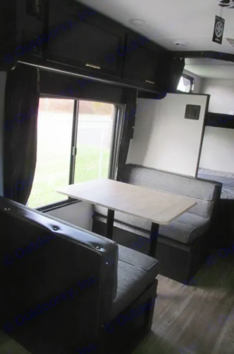 Cozy RV rental interior featuring a practical dinette with comfortable seating, large window, and overhead storage. Ready for adventures!. Forest River Cherokee Grey Wolf 2021