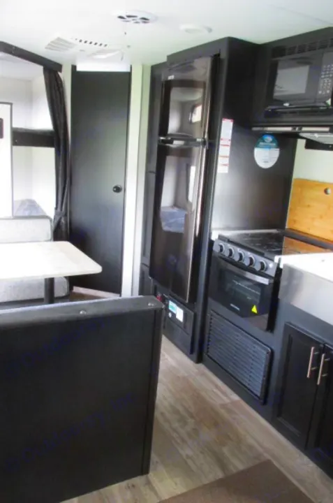 Modern rv rental interior: dark kitchen cabinets, stainless fridge, microwave, stove, and a comfy dinette. Ready for your adventure.. Forest River Cherokee Grey Wolf 2021
