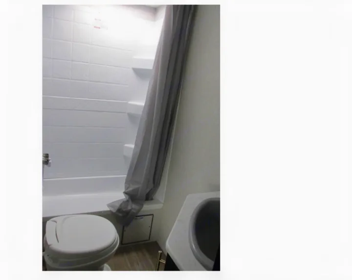 Compact RV rental bathroom with a white toilet, shower, and sink. Ideal for travel.. Forest River Cherokee Grey Wolf 2021