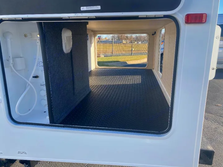 An RV rental's spacious pass-through storage bay, with water hookups, a hand shower, and a durable diamond plate floor.. Jayco Redhawk 2021
