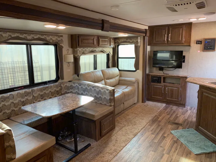 RV rental's inviting interior: U-shaped dinette, comfortable sofa, entertainment center, and warm wood accents.. Keystone Cougar Half-Ton 2017