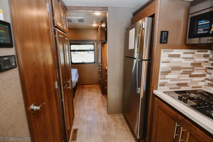 RV rental interior: compact kitchen with stainless appliances, leading to a cozy bedroom.. Thor Motor Coach Other 2021