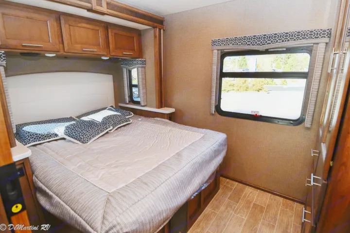 Comfortable RV rental bedroom with a large bed, overhead storage, and two windows, ideal for travel.. Thor Motor Coach Other 2021