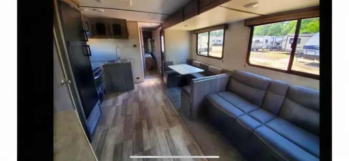 Modern RV rental interior with a fully equipped kitchen, spacious dinette, sofa, and a bedroom visible in the rear.. crossroads Volante 2020